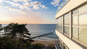 Un bâtiment moderne doté de grandes fenêtres donnant sur une plage et l’océan.
