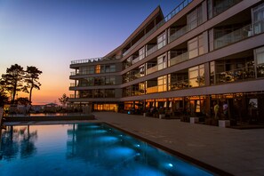 Un hotel de varios pisos con piscina y zona de estar al aire libre.