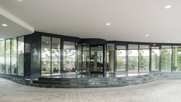 A modern building with a curved glass entrance, a tiled floor, and a view of the surrounding area. - Hotel Schopenhauer Hof (Frankfurt)