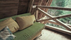 Una cabaña de madera con un sofá verde y vigas de madera.