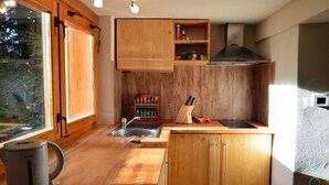 Una cocina compacta con armarios de madera, estufa integrada y una ventana que proporciona luz natural.