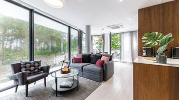 A modern living room with a grey sectional sofa, a glass coffee table, and a wooden accent wall.
