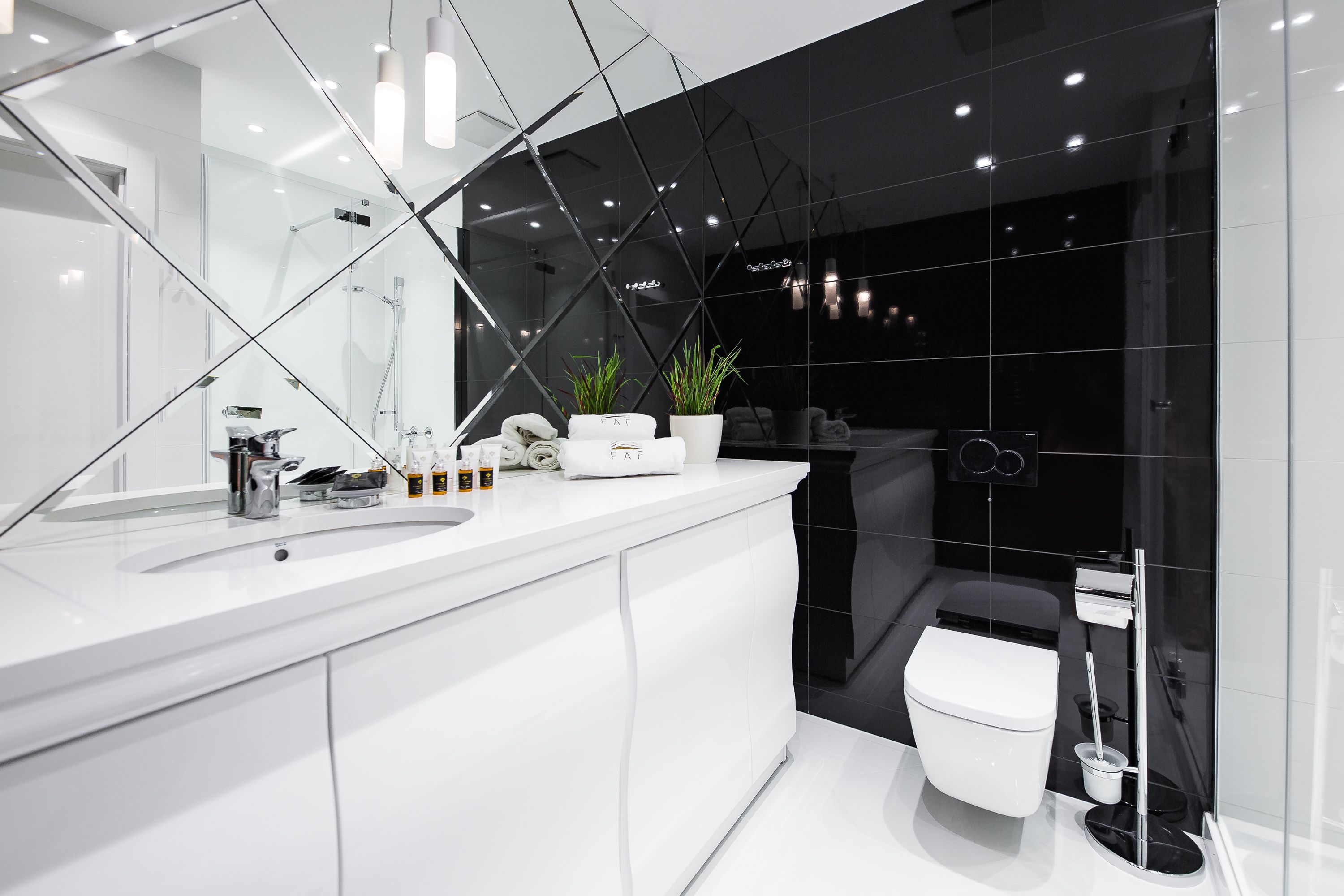 A modern bathroom with a white vanity, a large mirror, and a black toilet.