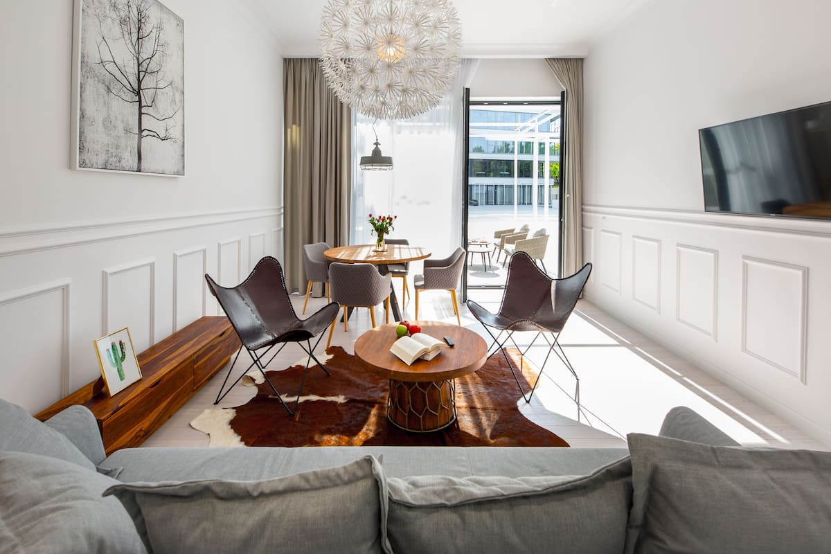 A modern living room with a sofa, a round wooden coffee table, and a dining area with chairs and a table.