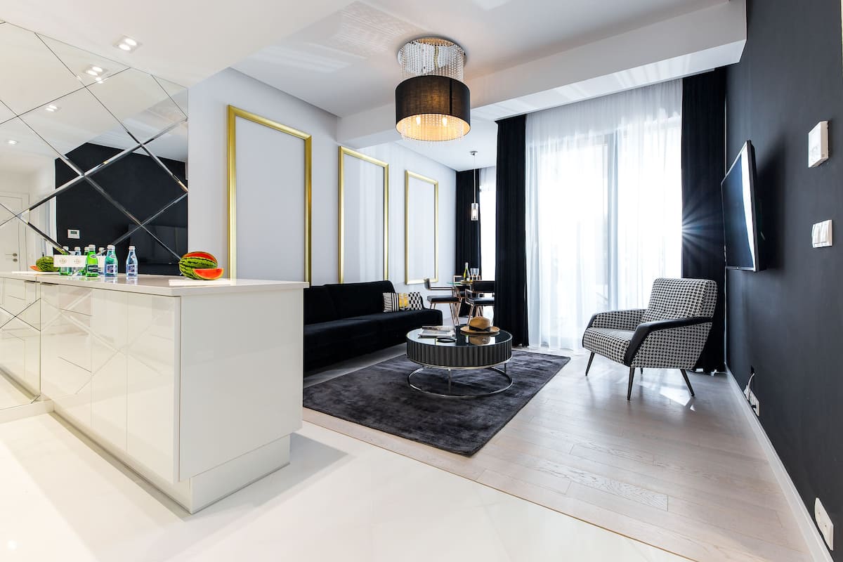 A modern living room with a black sofa, a round coffee table, and a black and white patterned armchair.