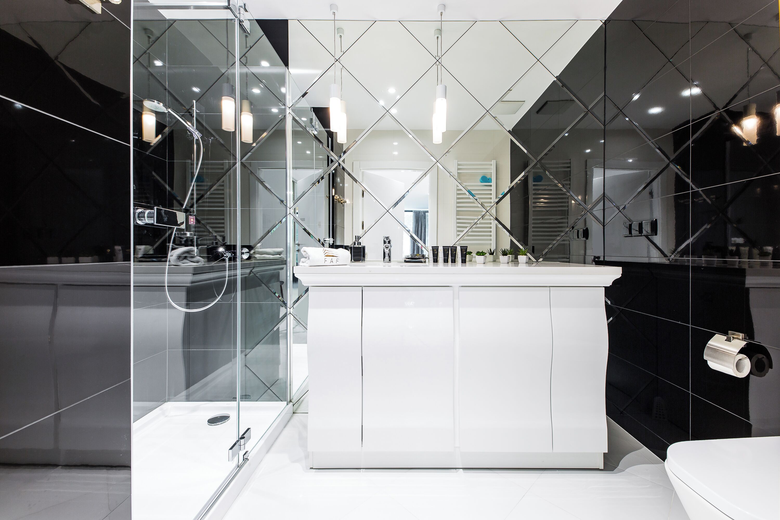 Une salle de bain moderne avec une cloison en verre, des meubles blancs et un îlot central.