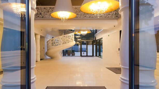 A modern hotel lobby with a spiral staircase, chandeliers, and a 'dune resort' sign on the floor. - DUNE B - FAF (Mielno)