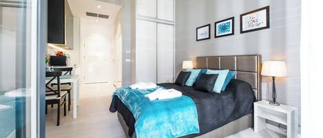 A modern bedroom with a bed, bedside tables, and a desk area.