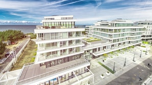 A modern multi-story building with large windows and balconies, situated near a waterfront. - DUNE B - FAF (Mielno)
