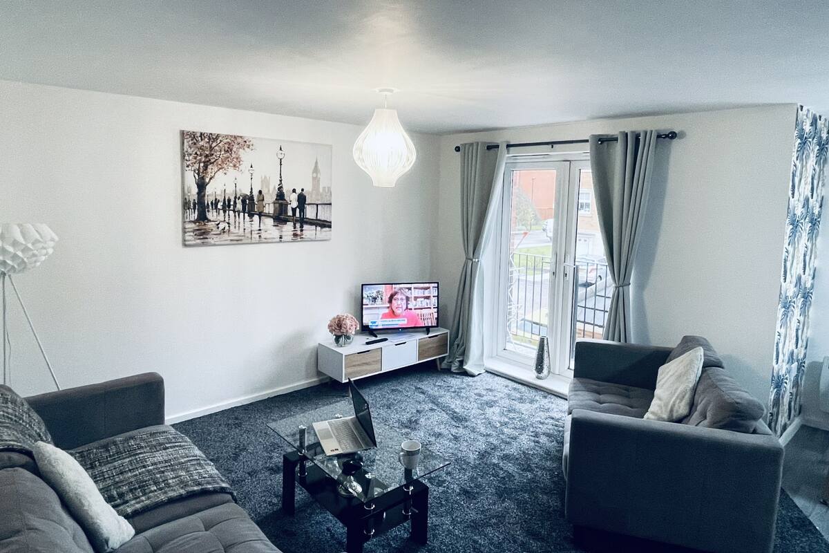 A modern living room with a sofa, a coffee table, a TV, and a painting on the wall.