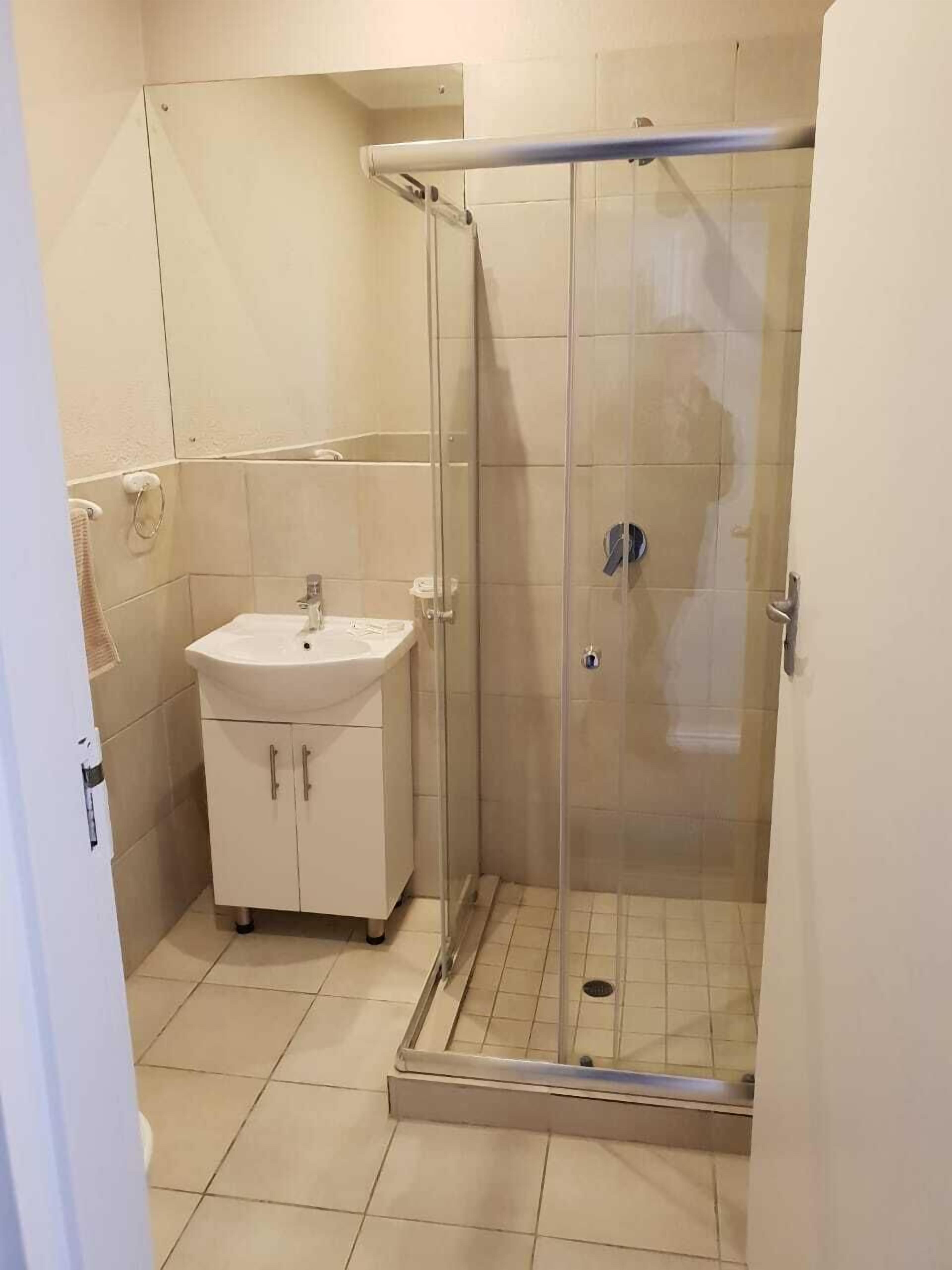 A bathroom with a glass-enclosed shower, a sink, and a toilet.