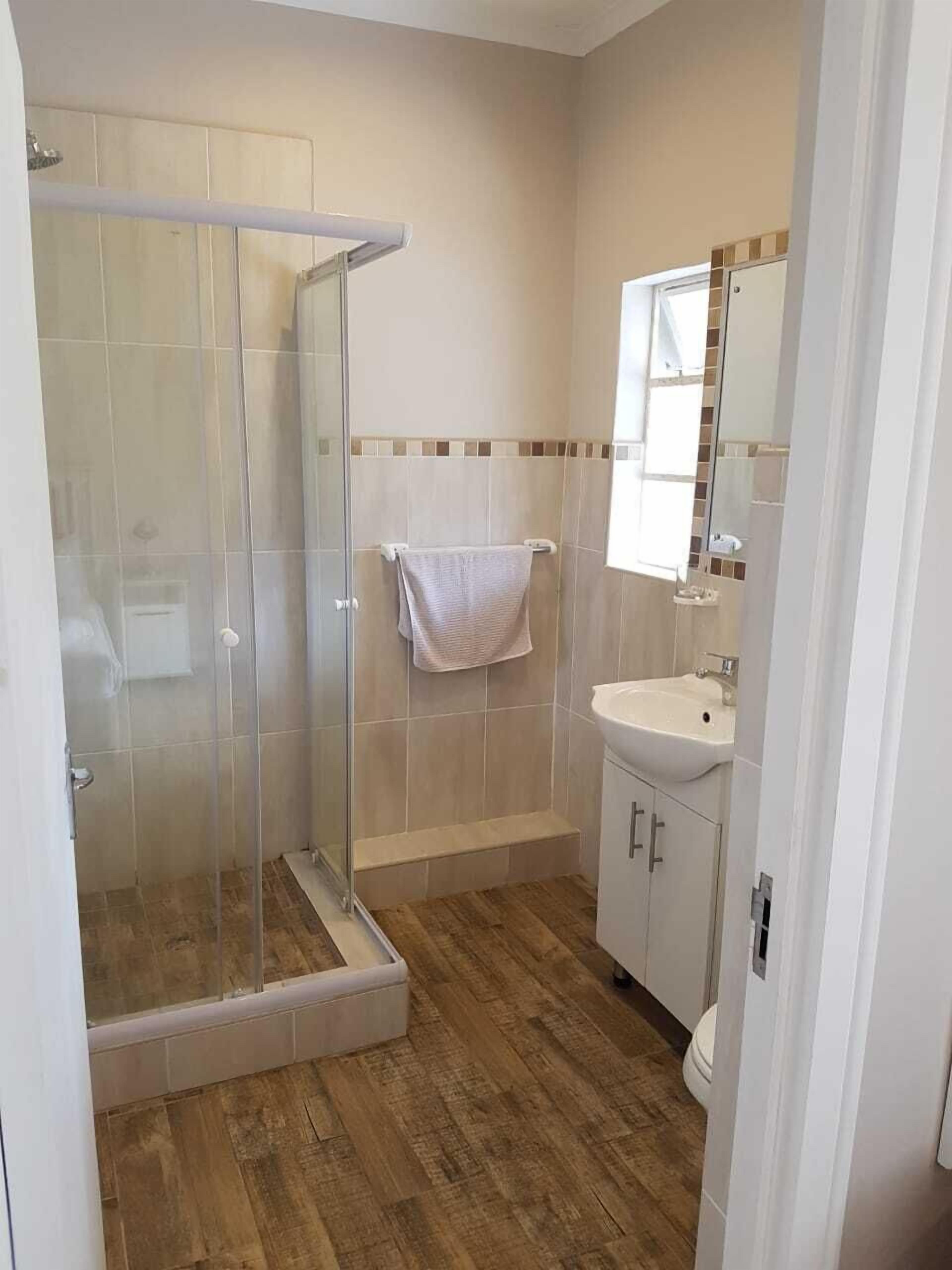 A bathroom with a glass shower enclosure, a sink, and a mirror.
