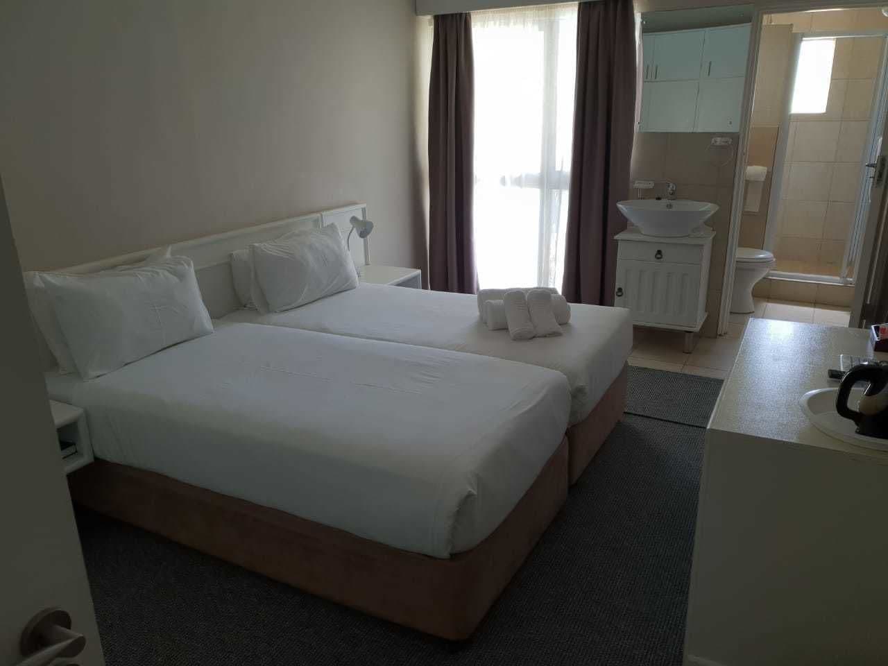Een hotelkamer met twee bedden, een badkamer en een douche.