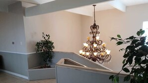 A modern interior with a central chandelier, a grey accent wall, and potted plants. - Savoy hotel (Jeffreys Bay)
