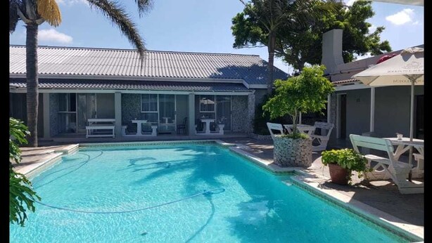 A swimming pool with lounge chairs and a covered seating area. - Savoy hotel (Jeffreys Bay)