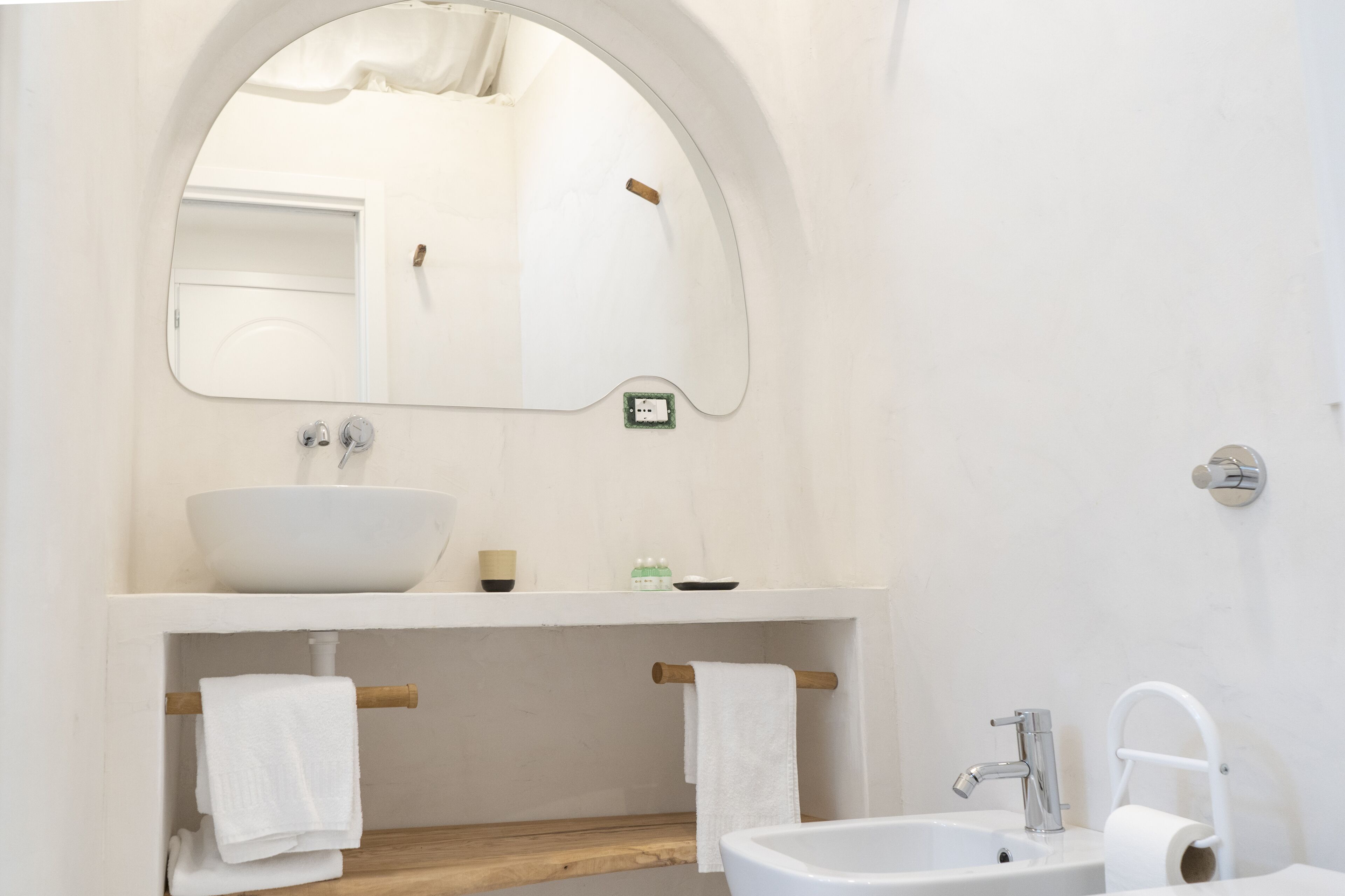 Une salle de bain moderne avec un lavabo blanc, un miroir, un porte-serviettes et un support à papier toilette.