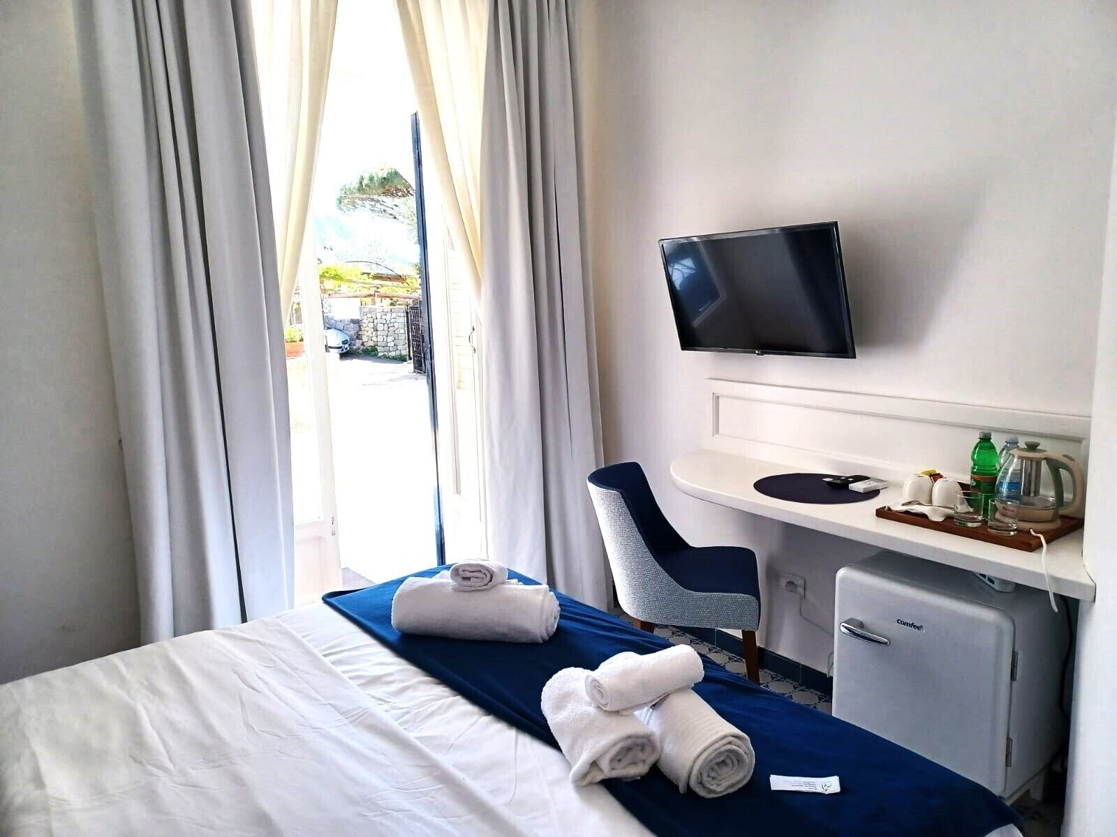 Een hotelkamer met een bed, een bureau met een televisie, een stoel en een koffiezetapparaat.