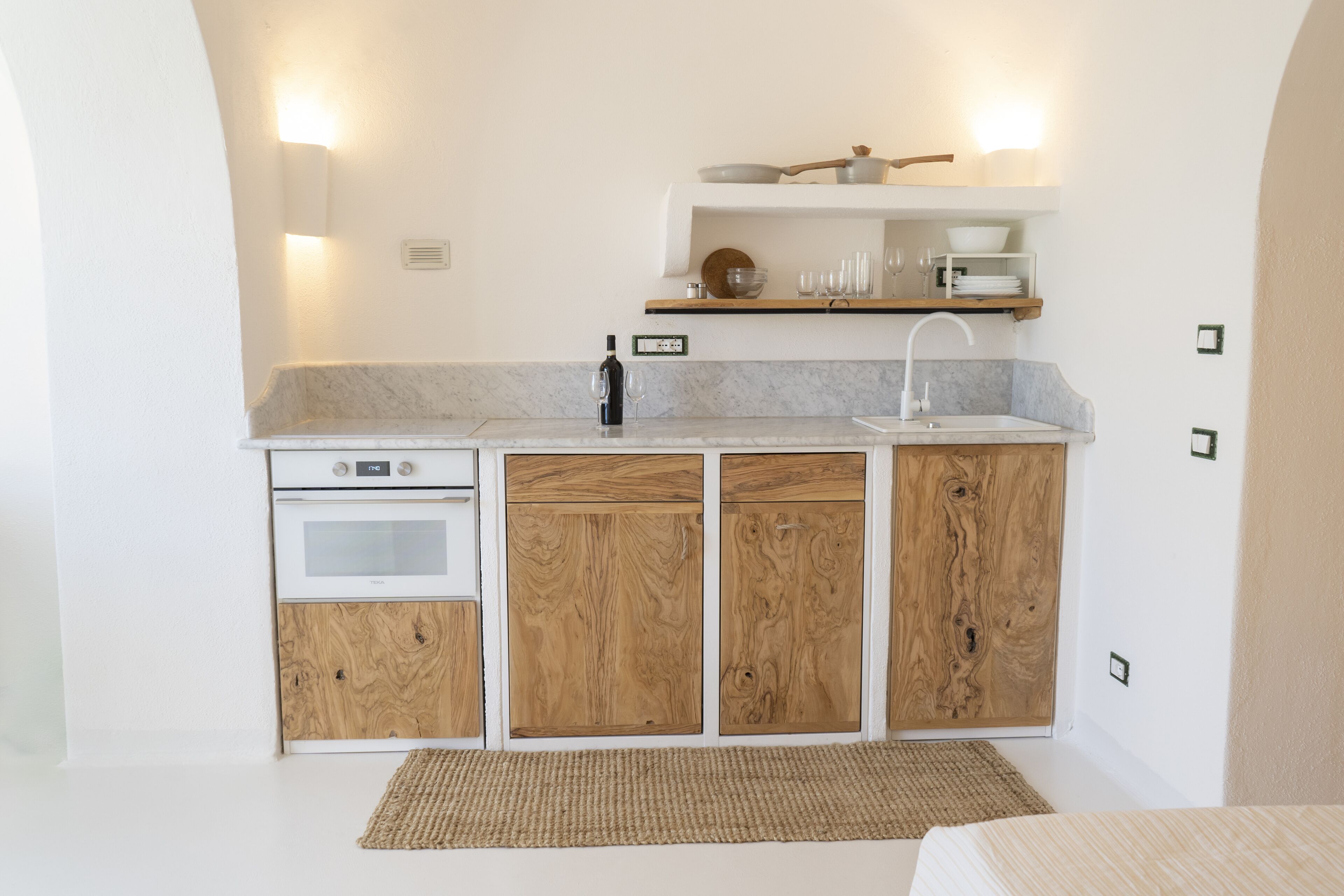A compact kitchen with a built-in oven, a sink, and wooden cabinets.