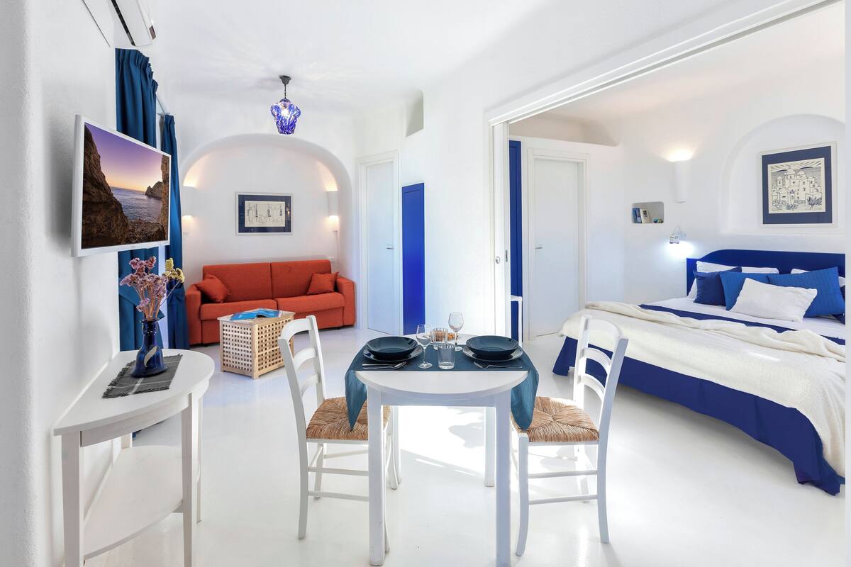 Una habitación de hotel moderna con zona de comedor, sofá y cama.