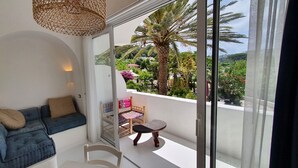 Un balcon avec un canapé bleu, une petite table et une lampe en osier.