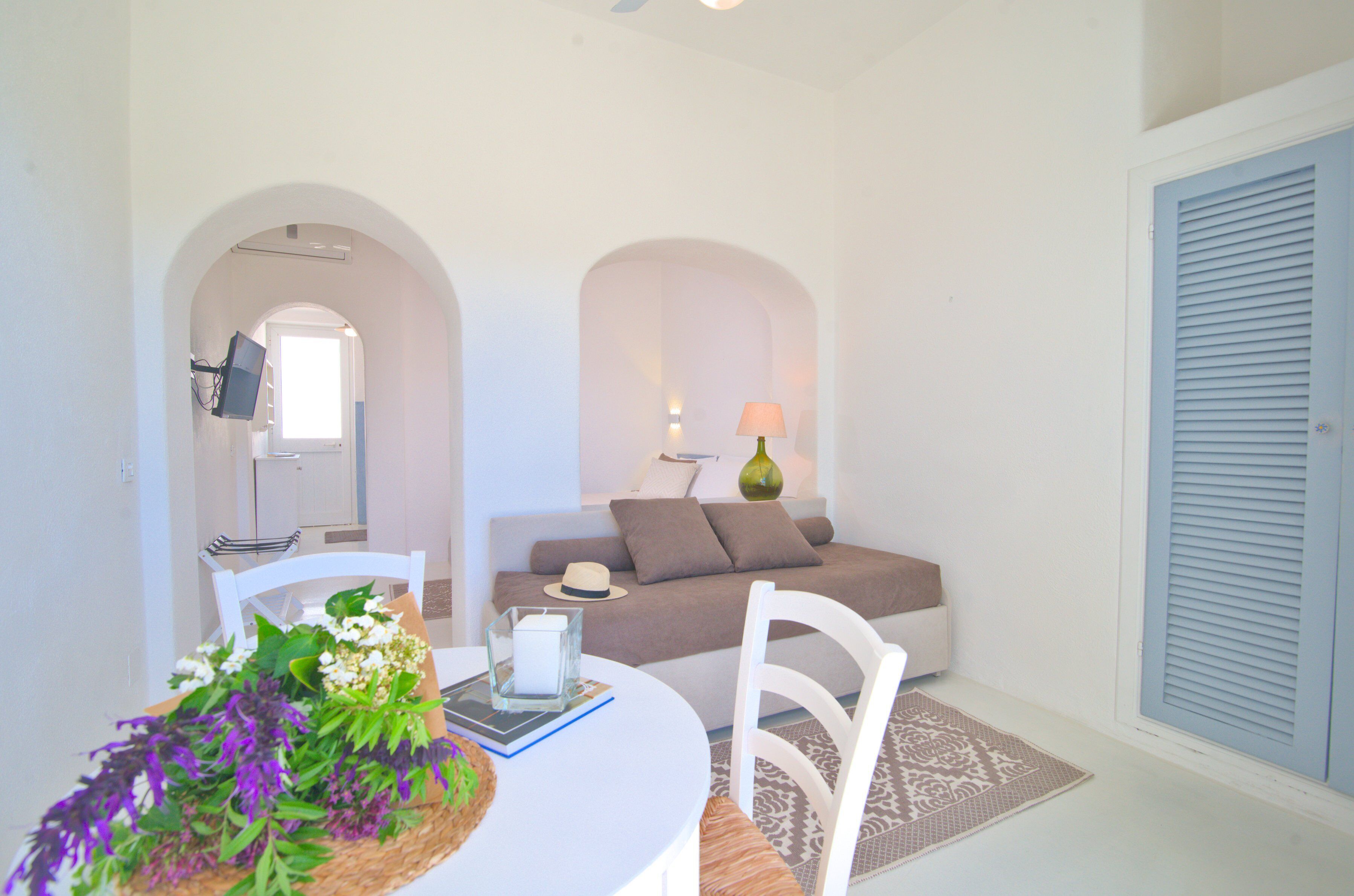 Una sala de estar moderna con un sofá blanco, una mesa de comedor con un jarrón de flores y una lámpara.