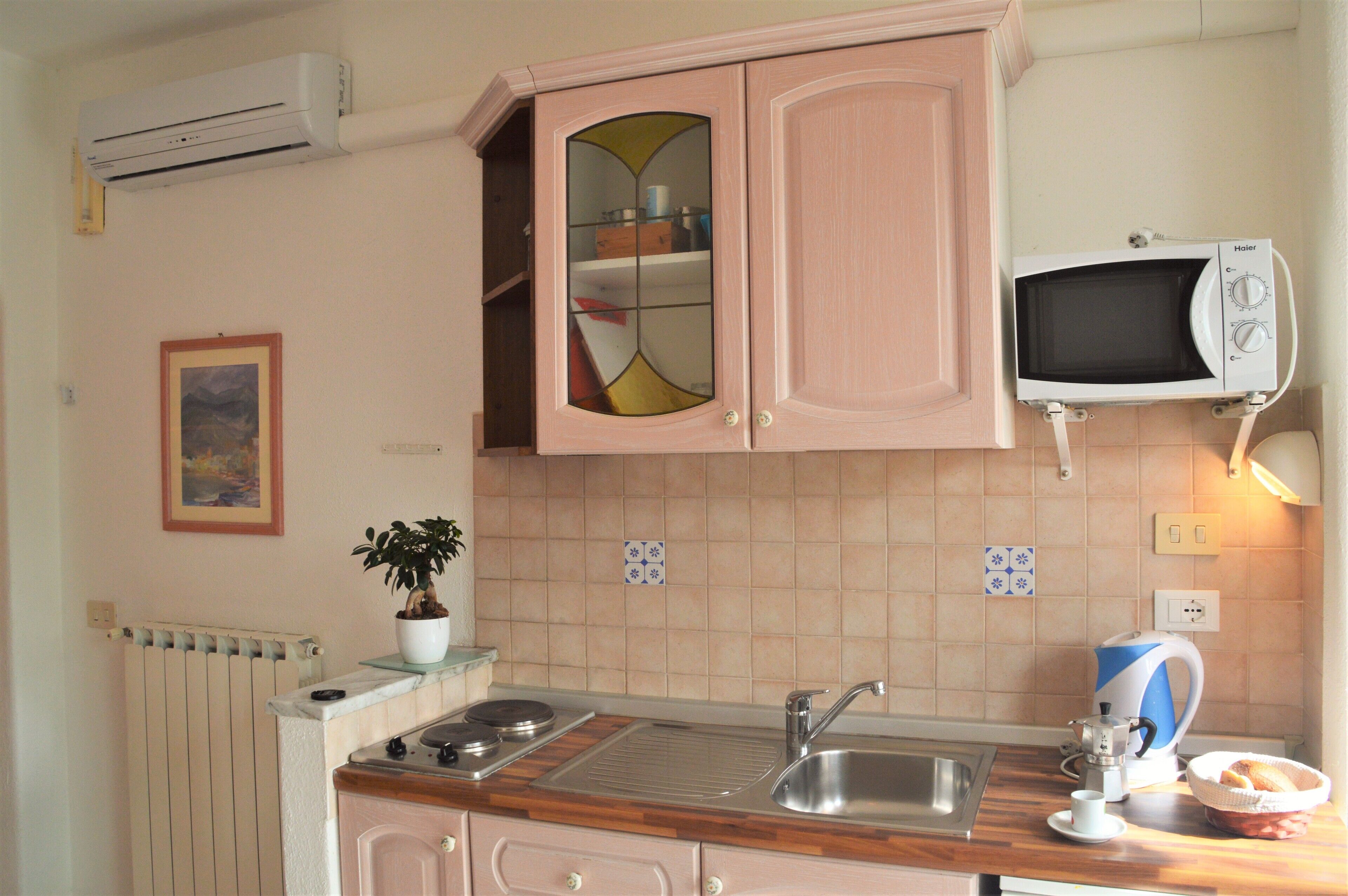 Una cocina con estufa, pileta y microondas.