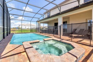 Una piscina con idromassaggio, circondata da un'area vetrata e arredata con lettini.