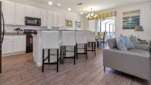A modern kitchen with white cabinets, a built-in oven, and a dining area with a gray sofa and patterned cushions. - Davenport - Stunning 6bd/5ba Poolhome - #6av331 (Davenport)