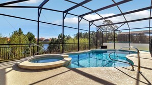 A covered outdoor swimming pool with a hot tub, surrounded by a metal fence, and overlooking a body of water. - Davenport - Stunning 6bd/5ba Poolhome - #6av331 (Davenport)