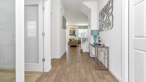 A hallway with wooden flooring, white walls, and a staircase leading to a living area. - Davenport - Stunning 6bd/5ba Poolhome - #6av331 (Davenport)