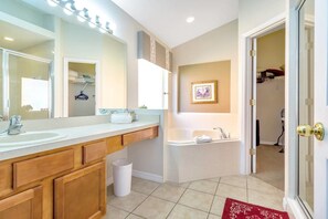 Un baño moderno con tocador doble, bañera y un espejo grande.