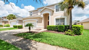 A residential house with a driveway, a garage, and a well-maintained lawn. - Emerald Island - 7bd/4.5ba Pool Home - #7ei565 (Kissimmee)