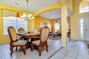A dining area with a wooden table and chairs, a chandelier, and a patterned wall. - Davenport - Spacious 6bd/5.5ba Pool Home-#6av151 (Davenport)