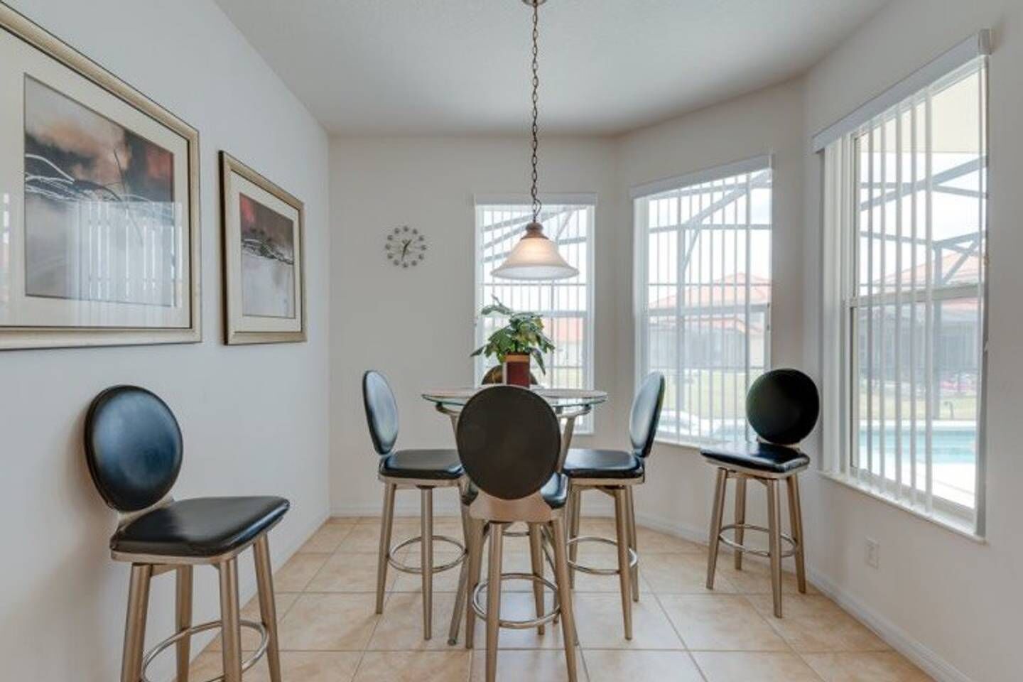 A dining area with a round table, four chairs, and a hanging light fixture.
