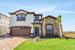 A two-story house with a brown garage, a stone accent wall, and a well-maintained lawn.