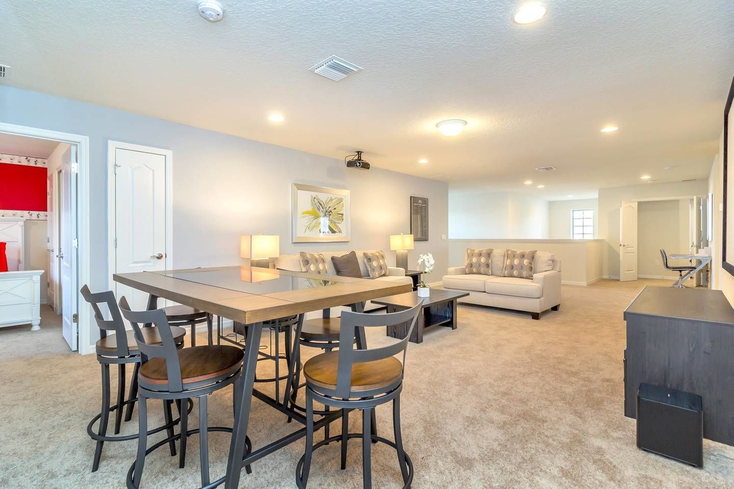 A spacious living room with a dining area, a sofa set, and a kitchen area with a countertop and chairs.