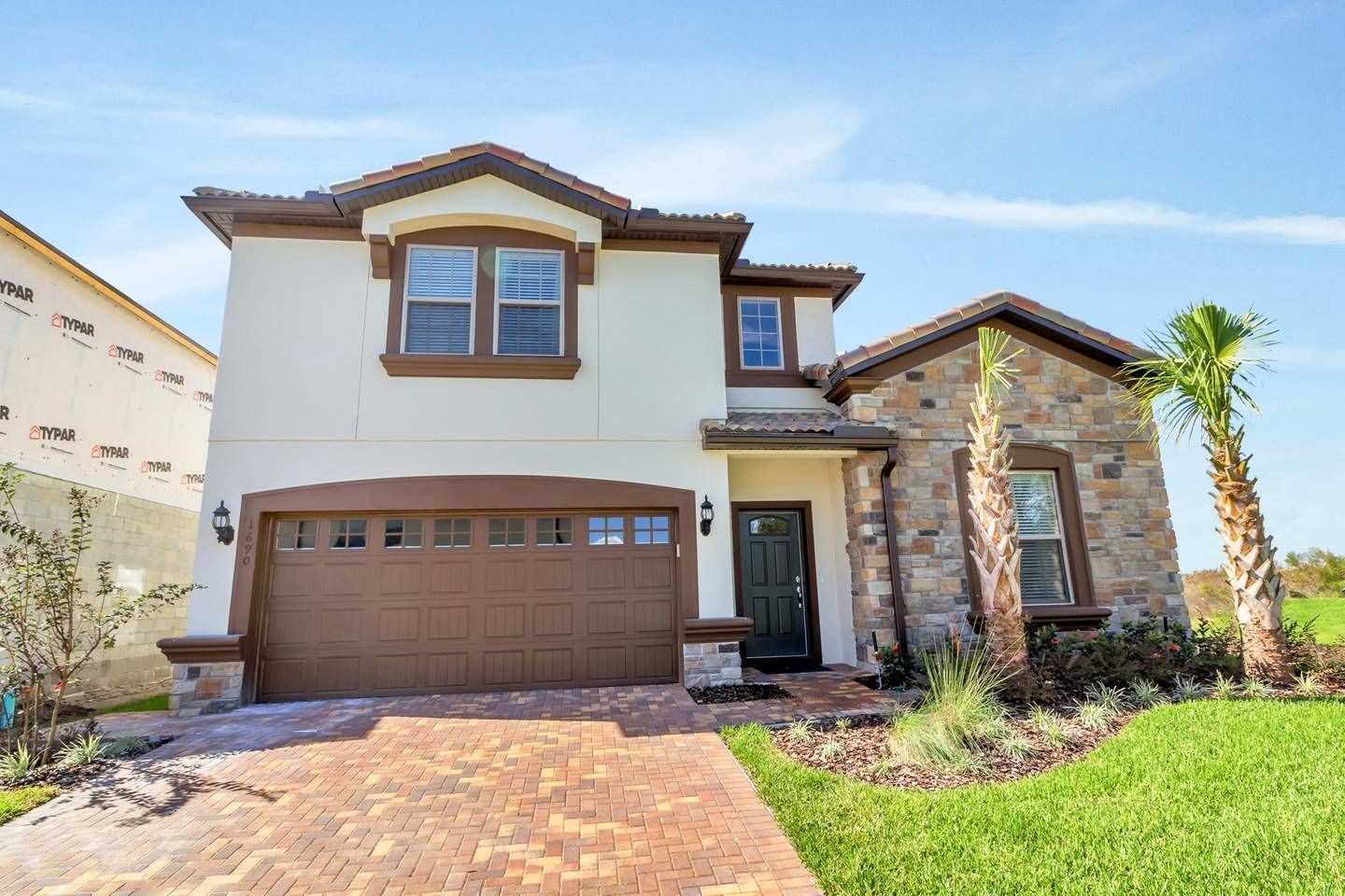 A two-story house with a garage, a stone exterior, and a well-maintained lawn.