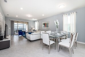 A modern living room with a glass dining table, white sofas, and a TV on a stand. - NEW DEC 2018! Solterra 6bd/4ba Pool Home #6st452 (Davenport)