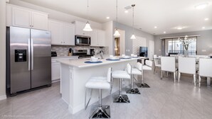 A modern kitchen with white cabinets, stainless steel appliances, and a central island with bar stools.