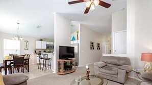 A modern living room with a sofa, a glass coffee table, and a television. - Hampton Lakes - Spacious 4bd/2ba Pool Home #4hl510 (Davenport)