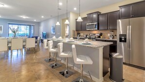 A modern kitchen with a central island, stainless steel appliances, and pendant lighting. - Solterra Resort 7BD Brand New Pool Home #7st565 (Davenport)