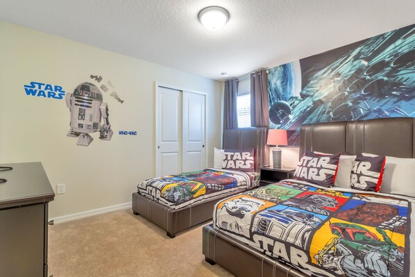A Star Wars-themed bedroom with two beds, a desk, and a wall decal of R2-D2.
