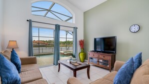 A spacious living room with a large window, a flat-screen TV, and a wooden cabinet.