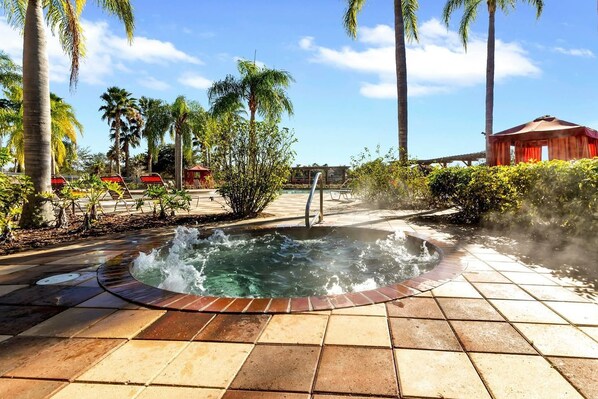 Relax in a serene hot tub surrounded by lush greenery and a tranquil patio.