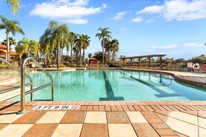 Relax by the pool surrounded by lush greenery and a covered seating area.