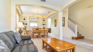 A living room with a sofa, coffee table, dining table, and chairs. There is a staircase leading to another level. - Davenport-6bd/5.5ba Pet-friendly Poolhome-#6av206 (Davenport)