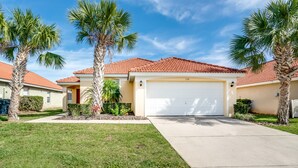 A residential house with a red-tiled roof, a white garage door, and palm trees in the front yard. - Aviana - Pet Friendly 4bd/3ba Pool Home - #4av136 (Davenport)