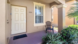 A beige building with a white door, a window, and a number "3908" on the wall.