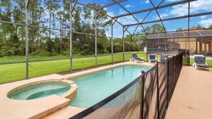 A covered swimming pool with a hot tub, surrounded by a fence, and equipped with lounge chairs. - Watersong - Luxurious 5bd/4.5ba Pool Home #5wr510 (Davenport)