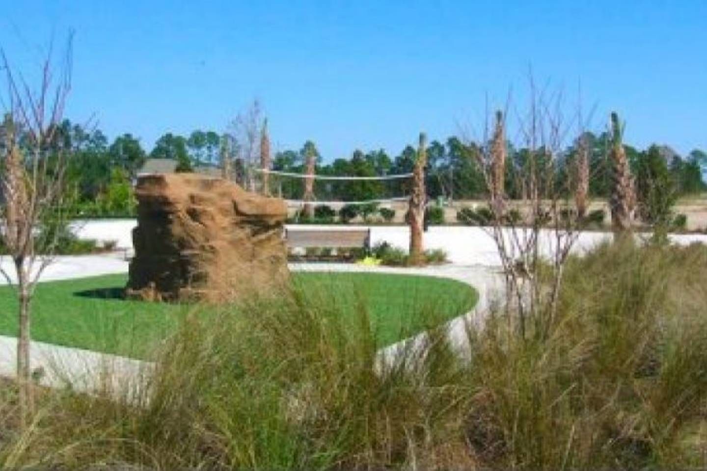 A stone structure surrounded by grass and trees in a landscaped area.